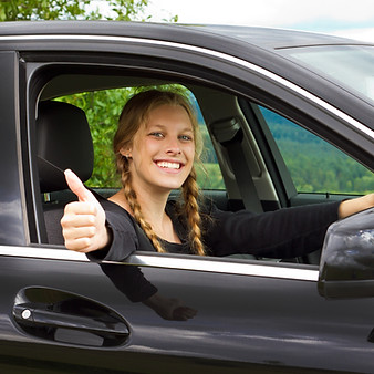 Happy young woman in a car with her thumb up