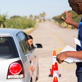 Driving instructor teaching learner driver to park a car in testing ground